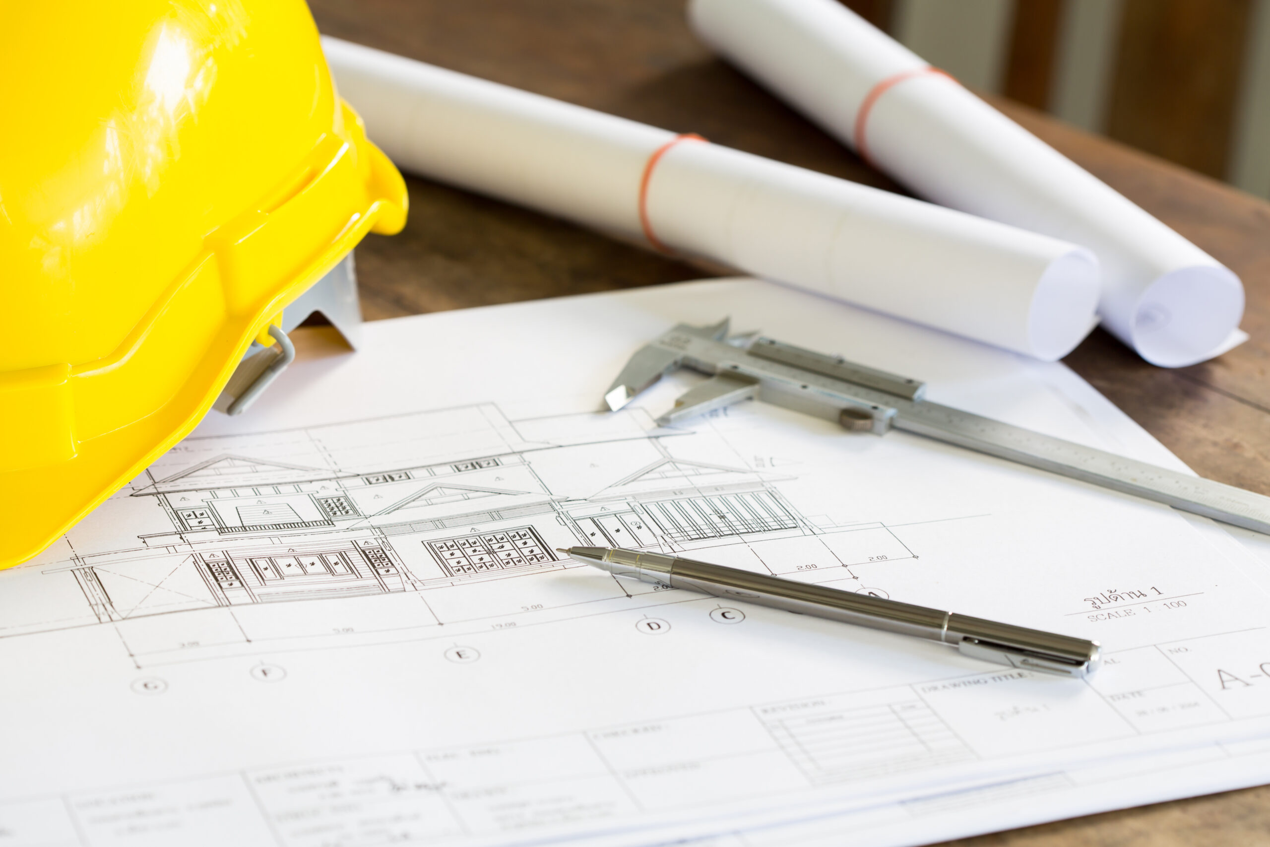 construction plans with yellow helmet and drawing tools on bluep